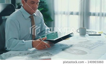 Skilled engineer look at mobile phone while working on tablet. Alimentation. 140903860