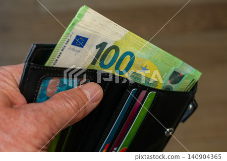 Hand Holding Black Leather Wallet Filled with 100 Euro Banknotes and Payment Cards, Finance concept Hand Holding Black Leather Wallet Filled with 100 Euro Banknotes and Payment Cards, Finance concept 140904365