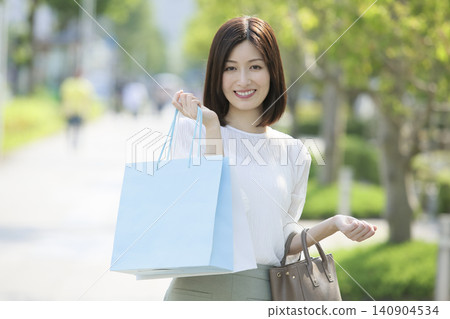 A woman on holiday, smiling and holding shopping bags. A woman on holiday, smiling and holding shopping bags. 140904534