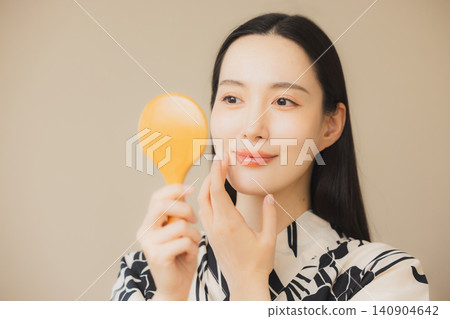 一位身穿浴衣的女子正在護膚。 一位身穿浴衣的女子正在護膚。 140904642