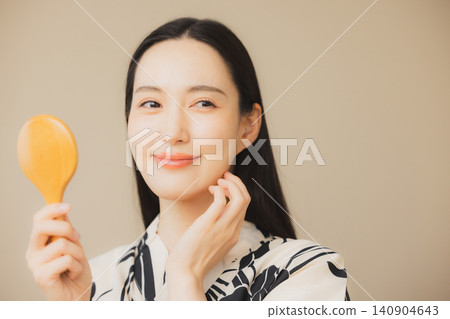 一位身穿浴衣的女子正在護膚。 一位身穿浴衣的女子正在護膚。 140904643