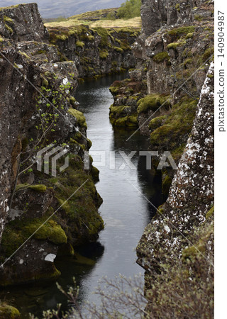 Glacial water filling a rocky volcanic fissure in a mossy rift valley, Iceland Glacial water filling a rocky volcanic fissure in a mossy rift valley, Iceland 140904987
