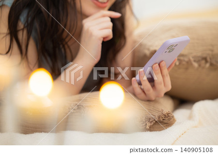一名婦女在床上的看一個智能手機 140905108