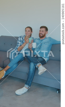 Vertical Video Panning waist-up shot of pleased smiling Caucasian husband and wife relaxing and drinking tea, sitting between cardboard boxes after house move. Vertical Video Panning waist-up shot of pleased smiling Caucasian husband and wife relaxing and drinking tea, sitting between cardboard boxes after house move. 140905181