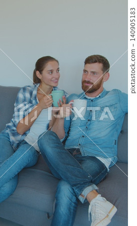 Vertical Video Panning waist-up shot of pleased smiling Caucasian husband and wife relaxing and drinking tea, sitting between cardboard boxes after house move. Vertical Video Panning waist-up shot of pleased smiling Caucasian husband and wife relaxing and drinking tea, sitting between cardboard boxes after house move. 140905183