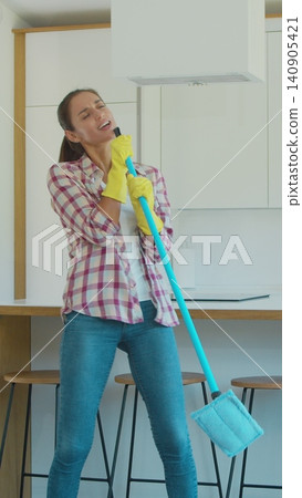 Vertical Video Young woman singing and dancing while cleaning her house. Vertical Video Young woman singing and dancing while cleaning her house. 140905421