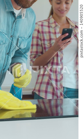 Vertical Video Man and woman as a professional cleaners in uniiform having fun during the work on the kitchen. 140905520