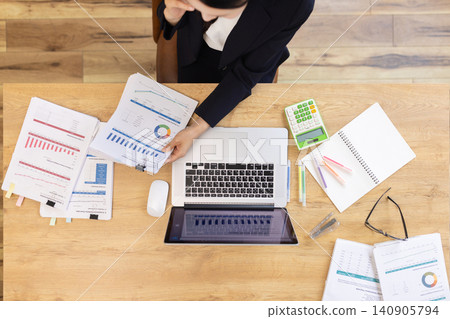 A businesswoman's laptop and documents on her desk (overhead view) A businesswoman's laptop and documents on her desk (overhead view) 140905794