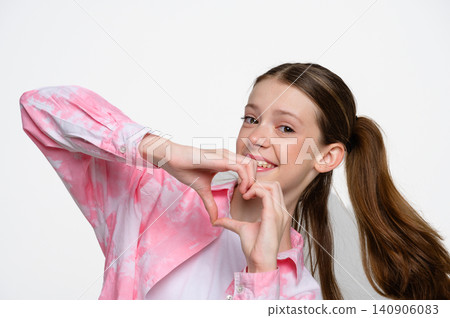 Smiling teenage girl forming heart shape with her hands. Smiling teenage girl forming heart shape with her hands. 140906083