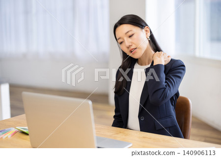 一位年輕的日本女商人坐在明亮的窗邊用筆記型電腦工作,她摸了摸自己的肩膀,似乎很痛苦。 一位年輕的日本女商人坐在明亮的窗邊用筆記型電腦工作,她摸了摸自己的肩膀,似乎很痛苦。 140906113