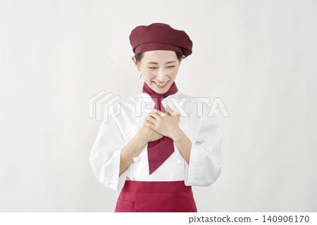 一位女糕點師面帶微笑，一手放在胸前。 140906170
