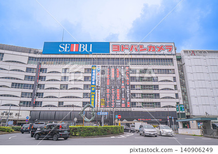 池袋站東口前的環形交叉路口及西武池袋總店的外景，以及友都八喜相機的招牌 [東京都豐島區南池袋] 140906249
