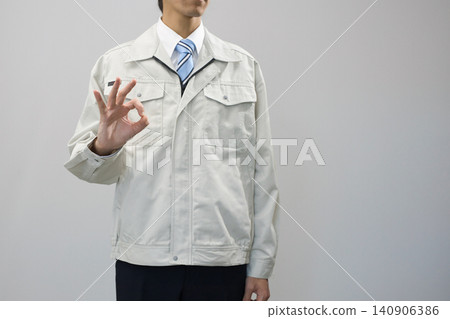 一位身穿工作服的年輕男子比出「OK」手勢。 一位身穿工作服的年輕男子比出「OK」手勢。 140906386