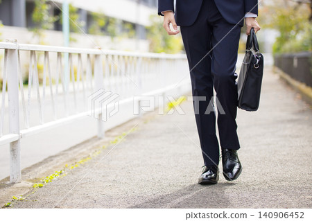 一位二十多歲的商人正在戶外散步。 一位二十多歲的商人正在戶外散步。 140906452