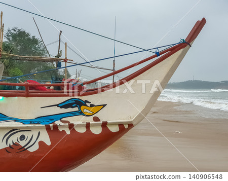 Traditional painted fishing boat on the shore at Weligama Beach in Sri Lanka on an overcast day Traditional painted fishing boat on the shore at Weligama Beach in Sri Lanka on an overcast day 140906548