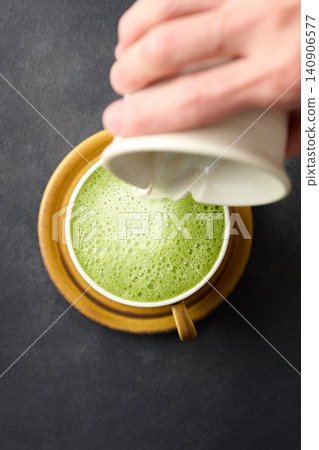 將抹茶拿鐵倒入杯中。 140906577