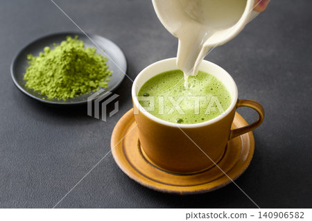 將抹茶拿鐵倒入杯中。 將抹茶拿鐵倒入杯中。 140906582