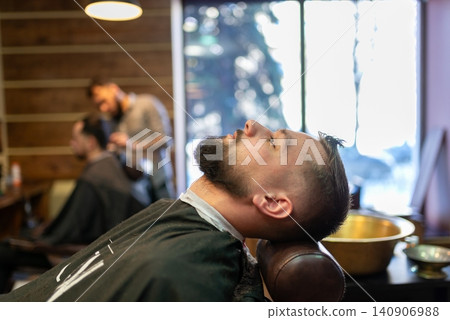 Man relaxing in chair before hair treatment process Man relaxing in chair before hair treatment process 140906988