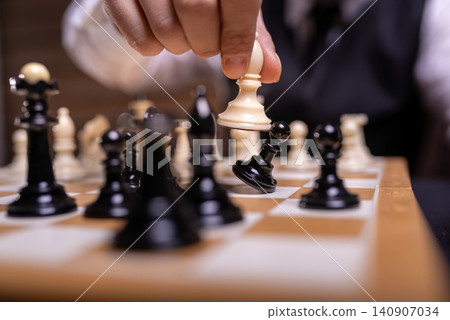 Hand knocking down a black pawn with a white chess piece Hand knocking down a black pawn with a white chess piece 140907034