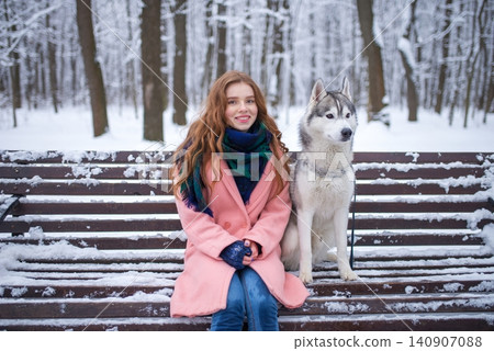 Young girl sitting on a snowy bench with a husky dog Young girl sitting on a snowy bench with a husky dog 140907088