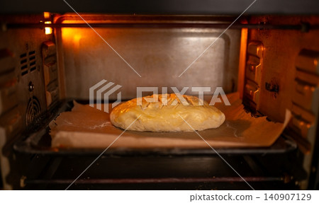 Scored bread loaf baking inside a hot oven Scored bread loaf baking inside a hot oven 140907129