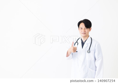 A middle-aged male doctor in a white coat gives a thumbs-up and makes a victory pose. A middle-aged male doctor in a white coat gives a thumbs-up and makes a victory pose. 140907254