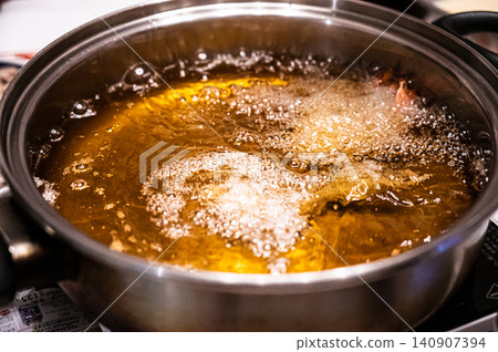 The process of cooking fried food in oil in a pot. 140907394