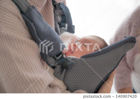 Baby looking up from inside the baby carrier 140907420