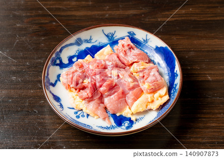 A plate of fresh chicken thigh meat cut for grilling. A plate of fresh chicken thigh meat cut for grilling. 140907873