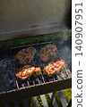 High angle shot of meat pieces grilling on metal rack over hot charcoal with smoke in outdoor barbecue grill. Ideal for summer food and restaurant advertising 140907951