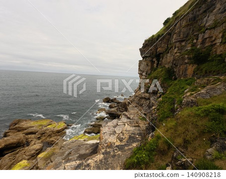 Rocky Sea Coast with Cliff and Ocean Under Dramatic Cloudy Sky 140908218