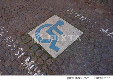Symbol of Accessibility Painted on Cobblestone Path for Public Awareness 140909366
