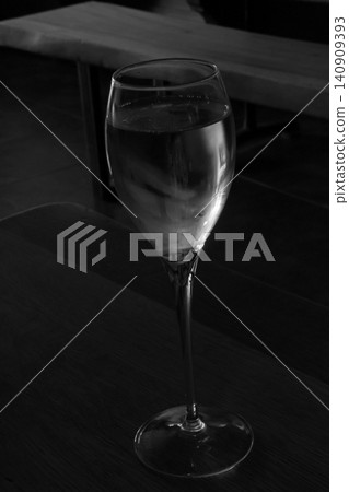 Elegant Wine Glass on Wooden Table in Dimly Lit Setting for Sophisticated Ambiance Elegant Wine Glass on Wooden Table in Dimly Lit Setting for Sophisticated Ambiance 140909393