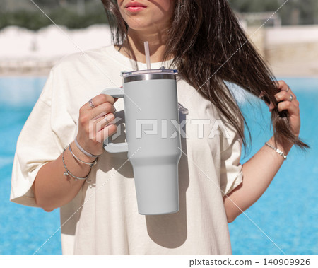 Blank grey 40oz tumbler mockup, young woman at poolside, hand close up. Lifestyle scene Blank grey 40oz tumbler mockup, young woman at poolside, hand close up. Lifestyle scene 140909926