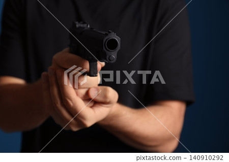 Man holding gun on dark background, closeup 140910292