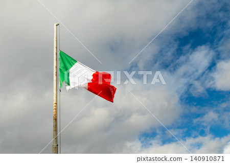 Italian flag waving on flagpole against cloudy sky Italian flag waving on flagpole against cloudy sky 140910871