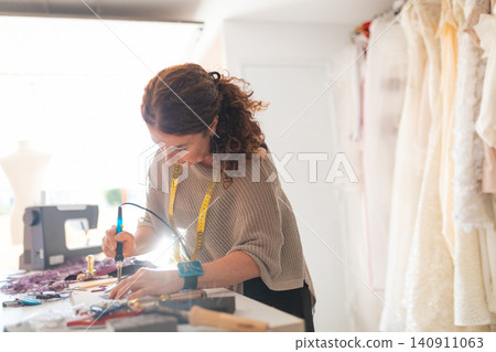 Craftswoman working on intricate details for custom clothing Craftswoman working on intricate details for custom clothing 140911063