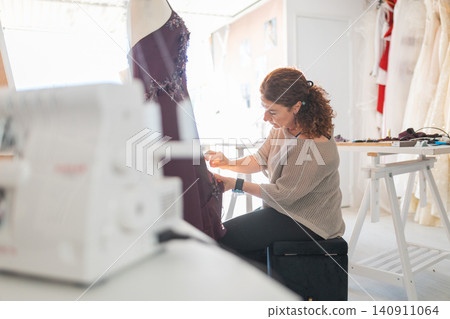 Female tailor creating custom gown in fashion atelier 140911064