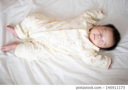 A full-body photo of a baby sleeping in a white blanket. A full-body photo of a baby sleeping in a white blanket. 140911173