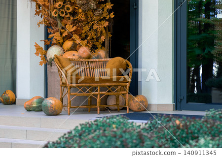A cozy outdoor seating area decorated for fall with pumpkins, sunflowers, and warm-toned leaves creating a welcoming atmosphere A cozy outdoor seating area decorated for fall with pumpkins, sunflowers, and warm-toned leaves creating a welcoming atmosphere 140911345