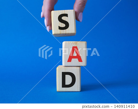 Sad symbol. Wooden cubes with words Sad. Businessman hand. Beautiful blue background. Business and Sad concept. Copy space. Sad symbol. Wooden cubes with words Sad. Businessman hand. Beautiful blue background. Business and Sad concept. Copy space. 140911410