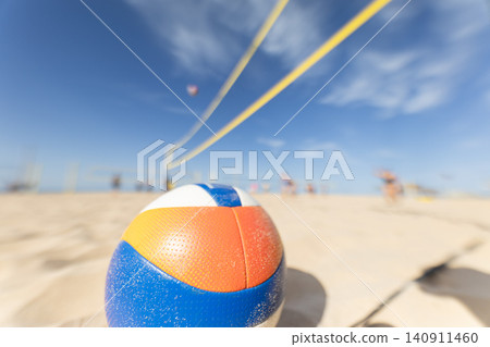 Beach volleyball game taking place on sunny day with court and ball in focus Beach volleyball game taking place on sunny day with court and ball in focus 140911460