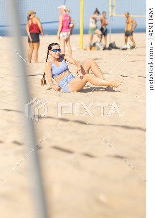 Beach volleyball game takes a break with players chatting and relaxing on sandy court Beach volleyball game takes a break with players chatting and relaxing on sandy court 140911465