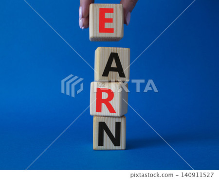 Earn symbol. Concept word Earn on wooden cubes. Businessman hand. Beautiful blue background. Business and Earn concept. Copy space. Earn symbol. Concept word Earn on wooden cubes. Businessman hand. Beautiful blue background. Business and Earn concept. Copy space. 140911527