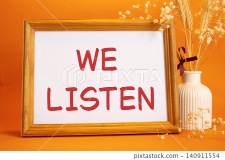 We listen symbol. Concept words We listen on beautiful wooden picture frame. Beautiful orange background with flower vase. Business and We listen concept. Copy space. We listen symbol. Concept words We listen on beautiful wooden picture frame. Beautiful orange background with flower vase. Business and We listen concept. Copy space. 140911554