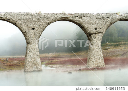 The Taushubetsu River Bridge in Kamishihoro Town, Hokkaido: A fantastical scene of an abandoned railway bridge enveloped in mist and autumn leaves. A tourist attraction. The Taushubetsu River Bridge in Kamishihoro Town, Hokkaido: A fantastical scene of an abandoned railway bridge enveloped in mist and autumn leaves. A tourist attraction. 140911653