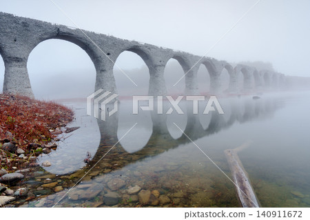 The Taushubetsu River Bridge in Kamishihoro Town, Hokkaido: A fantastical scene of an abandoned railway bridge enveloped in mist and autumn leaves. A tourist attraction. The Taushubetsu River Bridge in Kamishihoro Town, Hokkaido: A fantastical scene of an abandoned railway bridge enveloped in mist and autumn leaves. A tourist attraction. 140911672