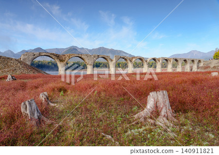 The Taushubetsu River Bridge in Kamishihoro Town, Hokkaido: A spectacular view of the former JNR Shihoro Line with autumn foliage and a clear blue sky. A tourist attraction. The Taushubetsu River Bridge in Kamishihoro Town, Hokkaido: A spectacular view of the former JNR Shihoro Line with autumn foliage and a clear blue sky. A tourist attraction. 140911821