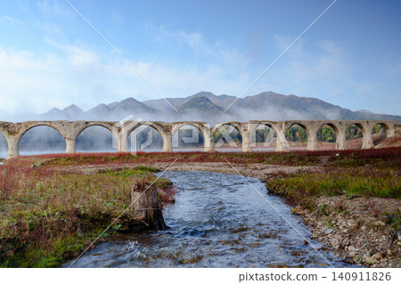 The Taushubetsu River Bridge in Kamishihoro Town, Hokkaido: A spectacular view of the former JNR Shihoro Line with autumn foliage and a clear blue sky. A tourist attraction. 140911826