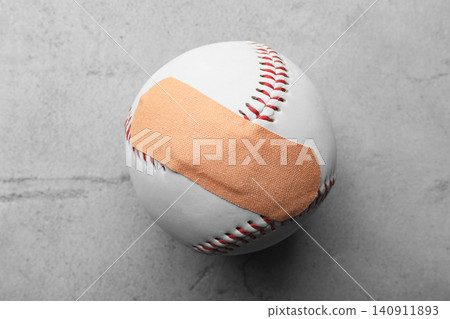 Ball with sticking plaster on light grey stone table, top view 140911893